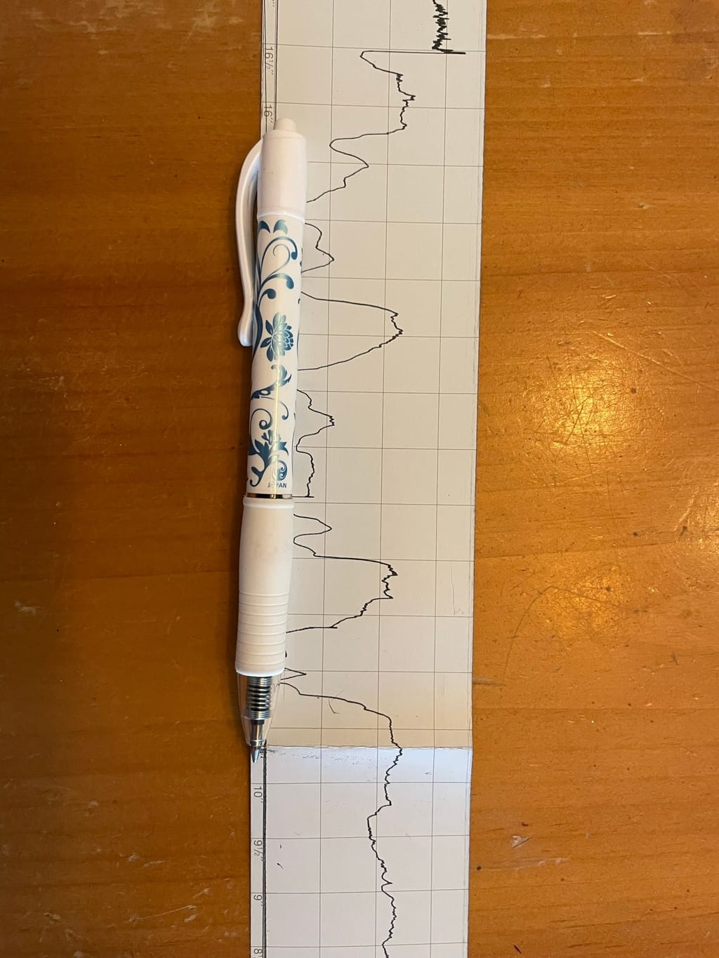 The same resistograph trace with a pen laid along it for scale, showing how far the decayed run extends across the strip.