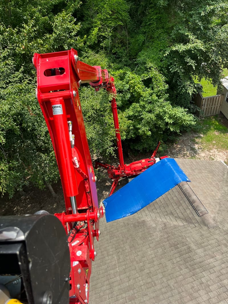 A tarped roof seen from the lift basket, with the boom rigged clear of the shingles.